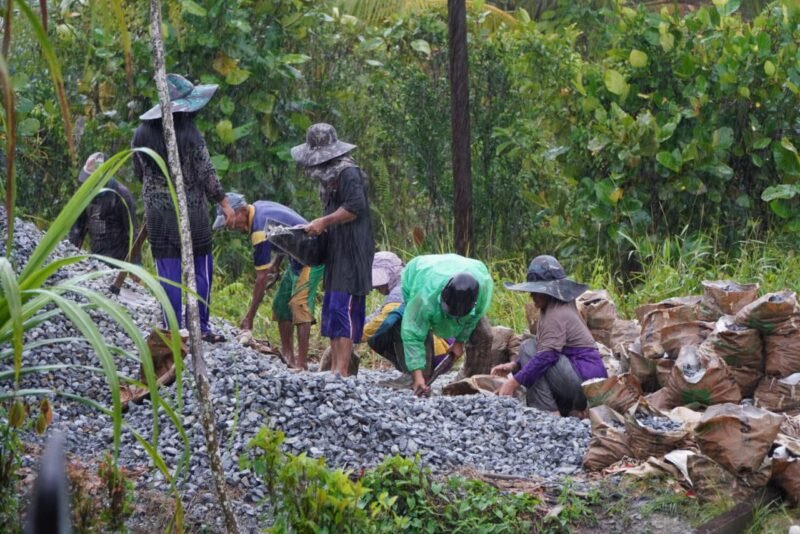 Meski Di Guyur Hujan Anggota Satgas TMMD ke 126 Kodim 1208/Sambas Tetap Semangat Angkut Material Untuk Rabat Beton