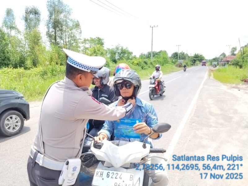 TargetNews.ID/Redaksi/Foto/Satuan Lalu Lintas – Dengan Senyuman yang ramah Personel Satlantas Polres Pulang Pisau mengingatkan pengendara roda dua agar selalu klik helm saat berkendara. Senin (17/11/2025).