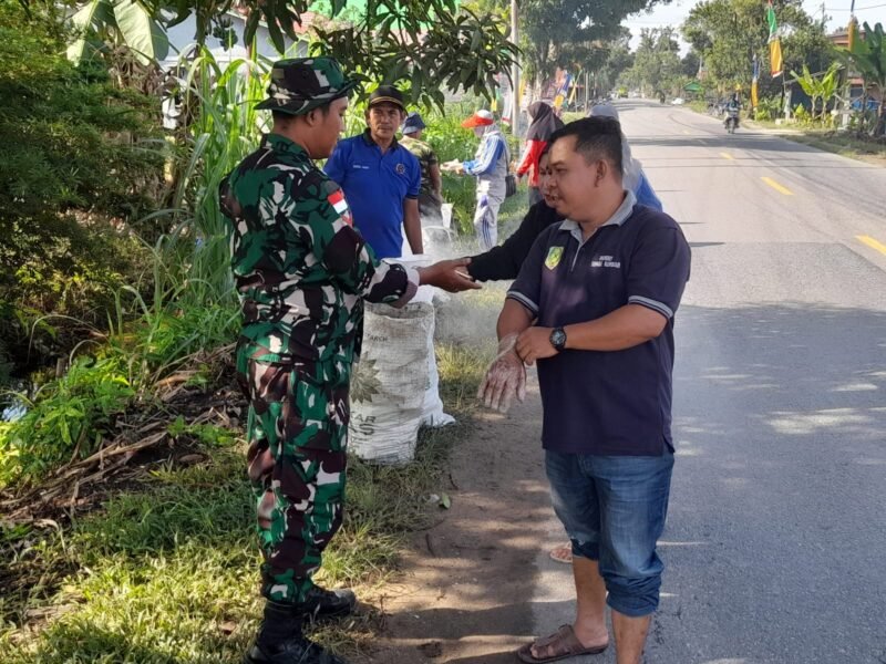 Babinsa Sungai Rambah Ajak Warga Gelar Karya Bakti Bersihkan Sampah di Kiri Kanan Jalan Raya Wilayah Binaan.