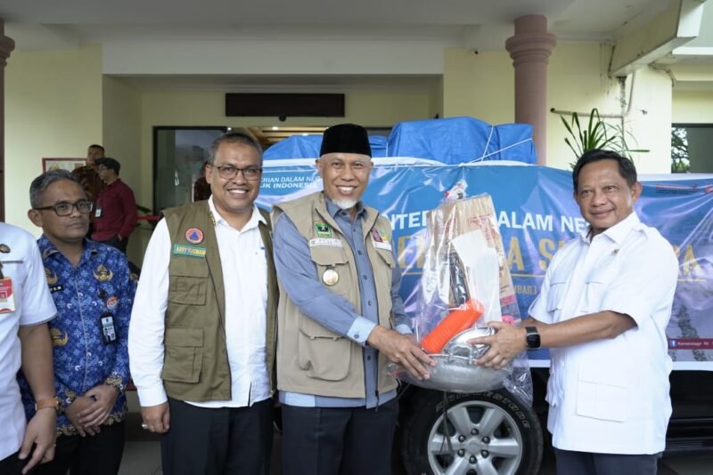 TargetNews.ID/Foto/Menteri Dalam Negeri (Mendagri) Muhammad Tito Karnavian menyerahkan bantuan secara simbolis kepada Gubernur Sumatera Barat (Sumbar) Mahyeldi Ansharullah di VIP Bandara Internasional Minangkabau (BIM), Kabupaten Padang Pariaman, Sumbar, Rabu (17/12/2025).