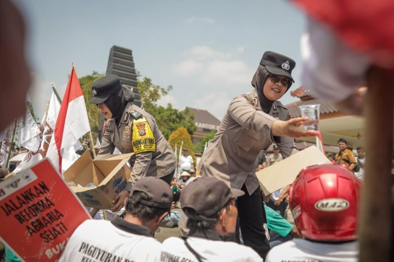 Foto: Polwan Polres Blitar membagikan air minum kepada peserta aksi reforma agraria di depan Kantor Pemerintah Kabupaten Blitar, Senin (21/9/2026). Usai aksi, personel Polwan turut membantu massa membersihkan sampah di lokasi kegiatan.