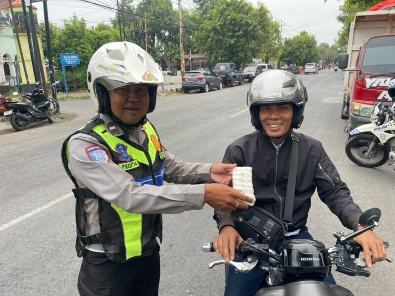 Kanit Turjawali Satlantas Polres Tegal IPTU Chrisna Adi Winata bersama anggota memberikan edukasi dan reward berupa sebungkus garam kepada pengendara sepeda motor yang tertib berlalu lintas di Jalan Aip KS. Tubun, Kabupaten Tegal, Selasa (27/10/2026).
