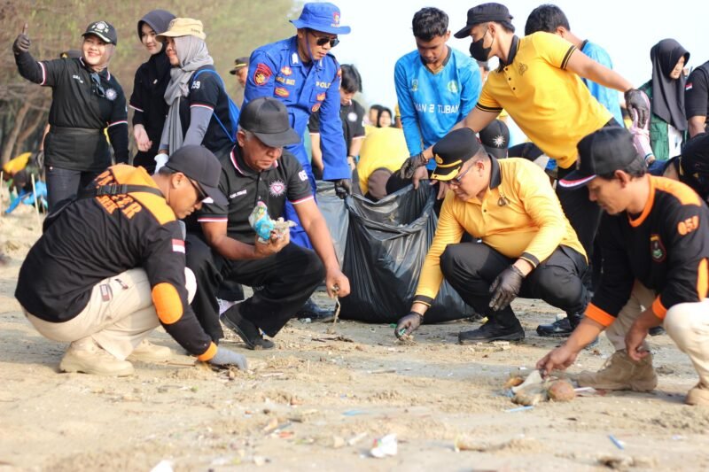 Wakapolresta Tuban AKBP Windy Syafutra bersama pesilat, mahasiswa, dan pelajar saat melaksanakan aksi bersih pantai serta penanaman 800 bibit cemara laut di Pantai Cemara, Desa Sugihwaras, Kecamatan Jenu, Kabupaten Tuban, dalam program Green Policing, Jumat (30/10/2026).